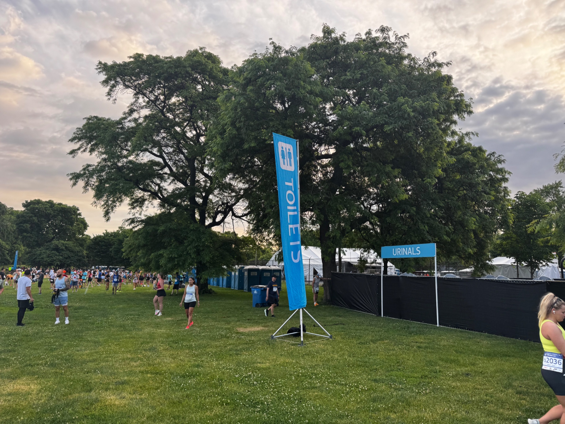 Toilets and urinals signage on the grass at Garfield Park with runners warming up