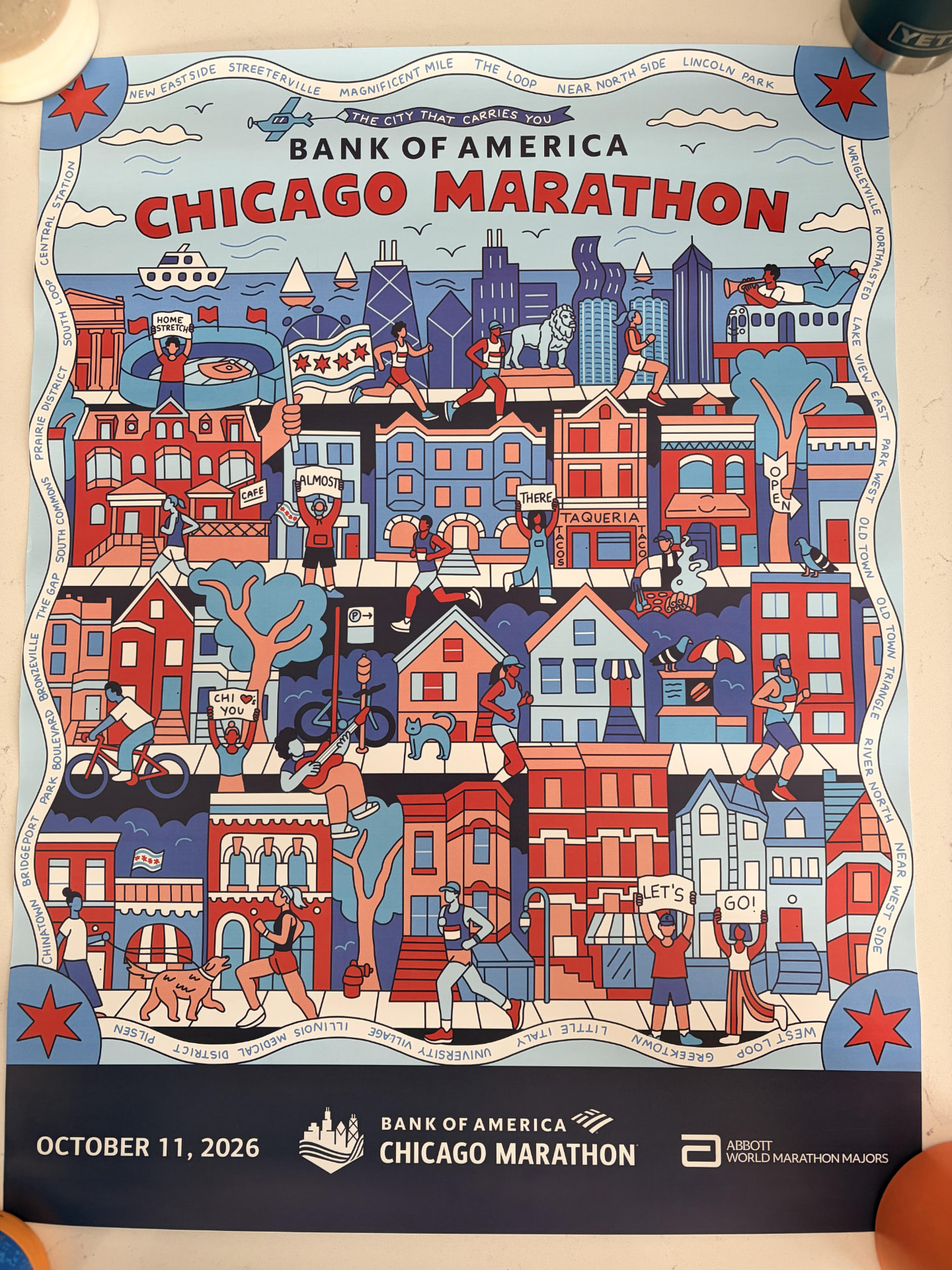 The 2026 Bank of America Chicago Marathon expo poster, an illustrated Chicago street scene with neighborhood names around the border and October 11, 2026 along the bottom