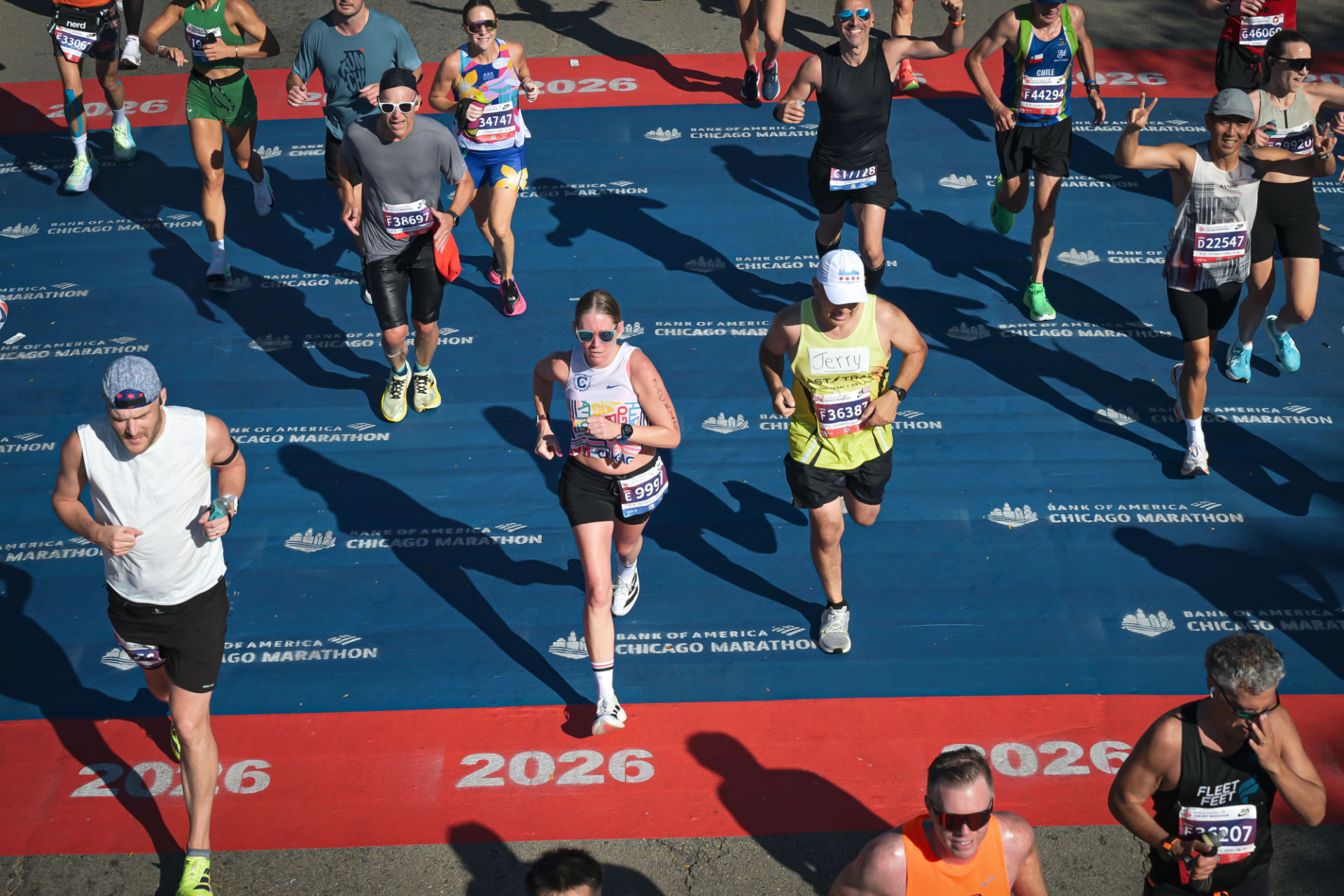Runners crossing the blue Bank of America Chicago Marathon finish-line track mat in Grant Park