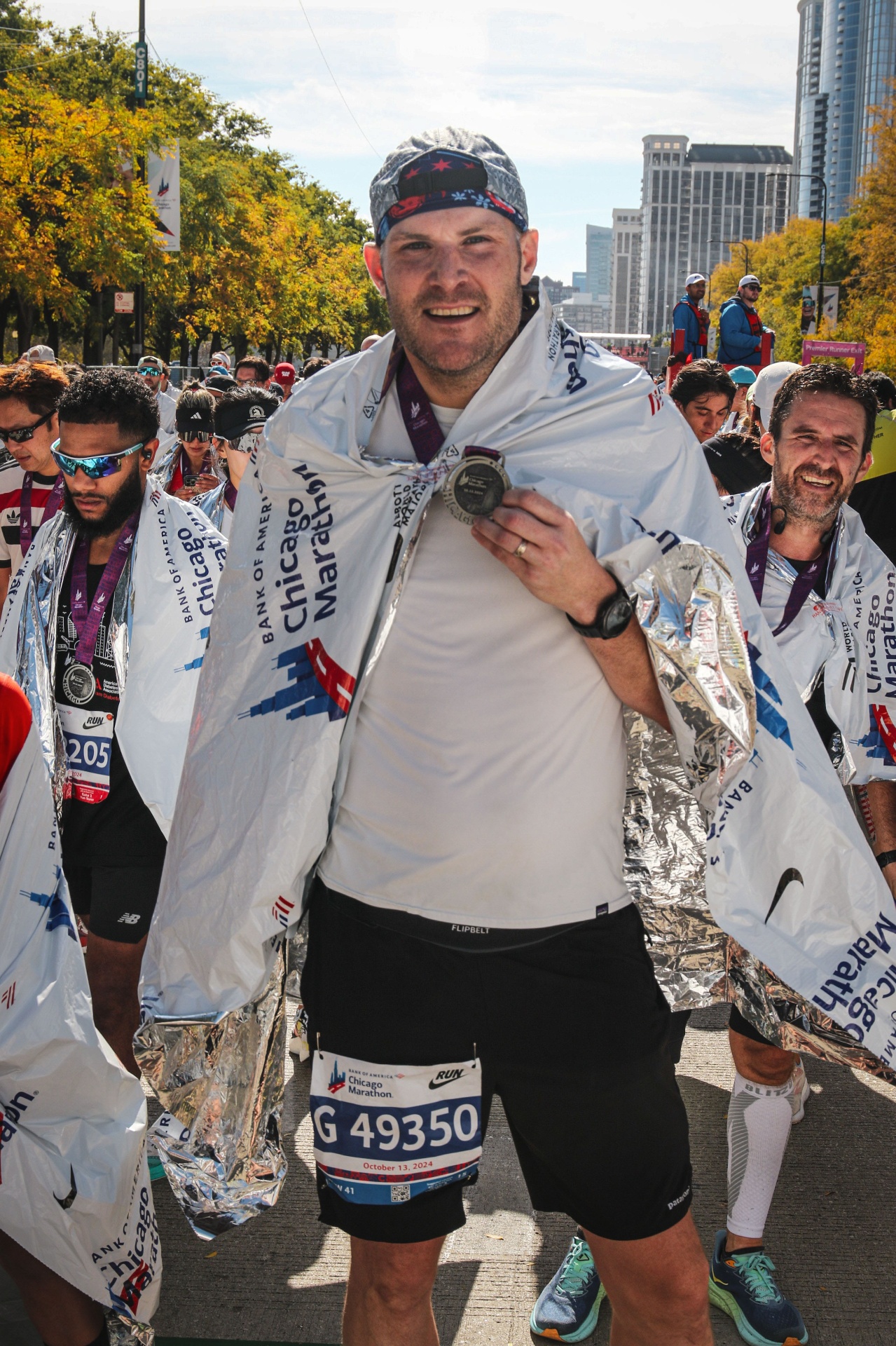 Alex at the Chicago Marathon 2024 finish line, wrapped in a finisher blanket with bib G49350